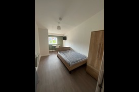 photograph of a bedroom with a double bed, bedside table, and wardrobe.